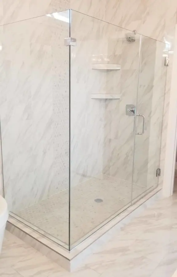 A bathroom with a glass shower door and tiled walls.