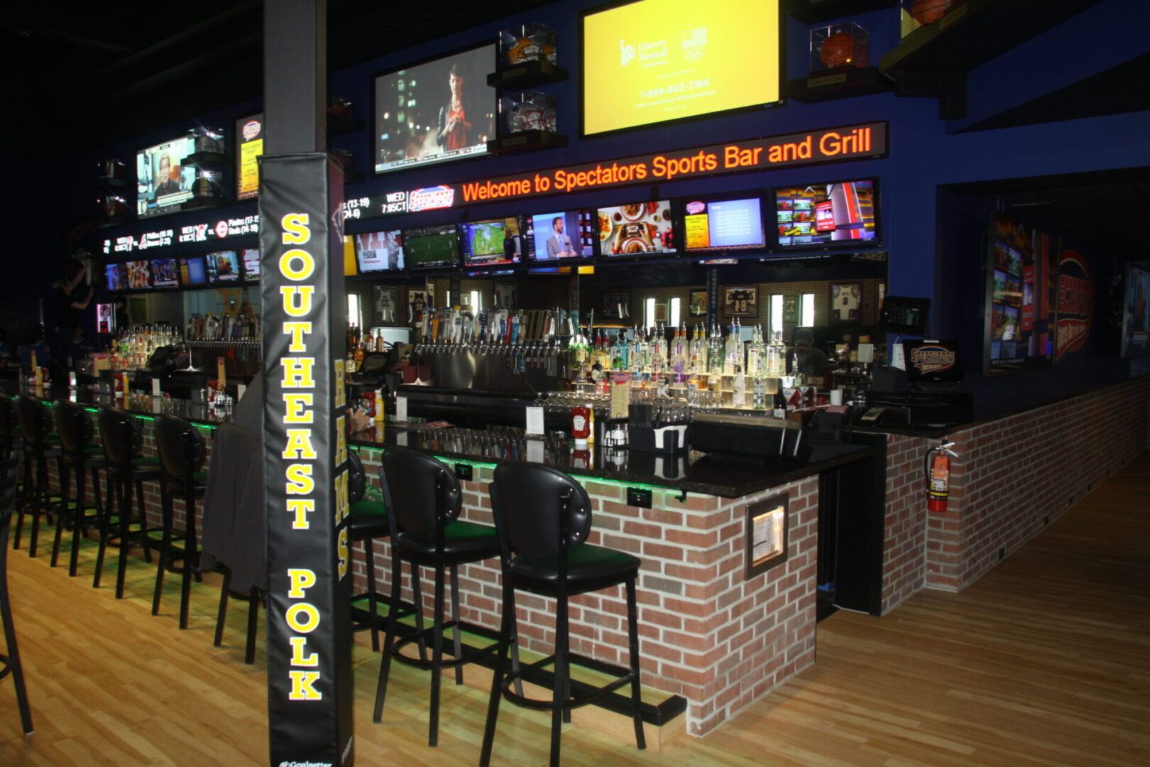 A bar with several black stools and tables.