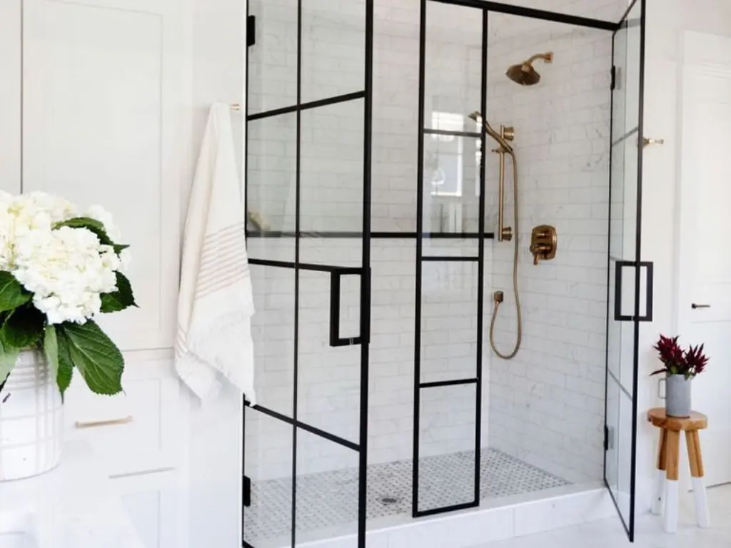 A bathroom with two shower stalls and a towel hanging on the wall.